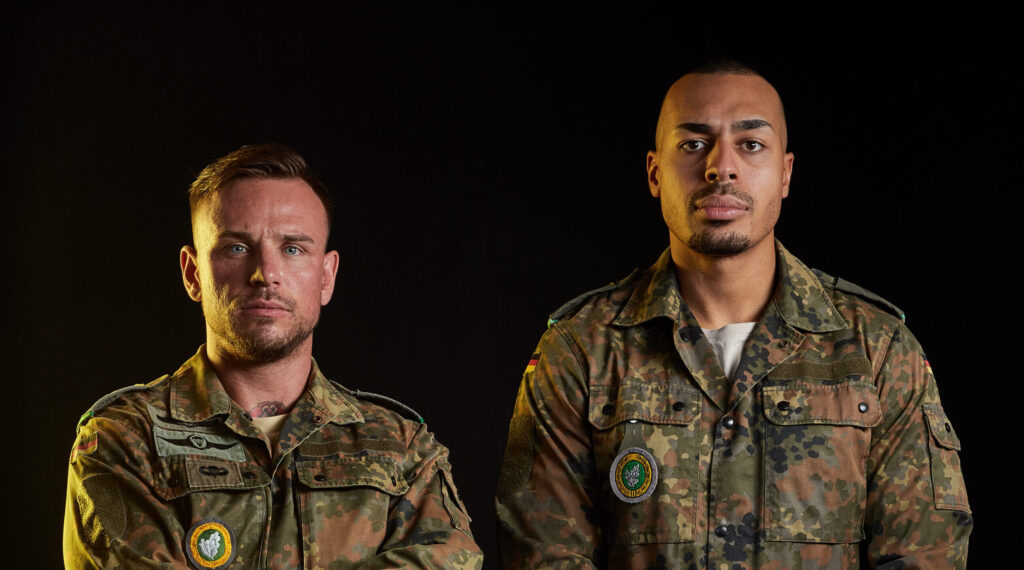 Denis Pfeifer und Samuel Come in Bundeswehr-Flecktarn, Portrait vor schwarzem Hintergrund